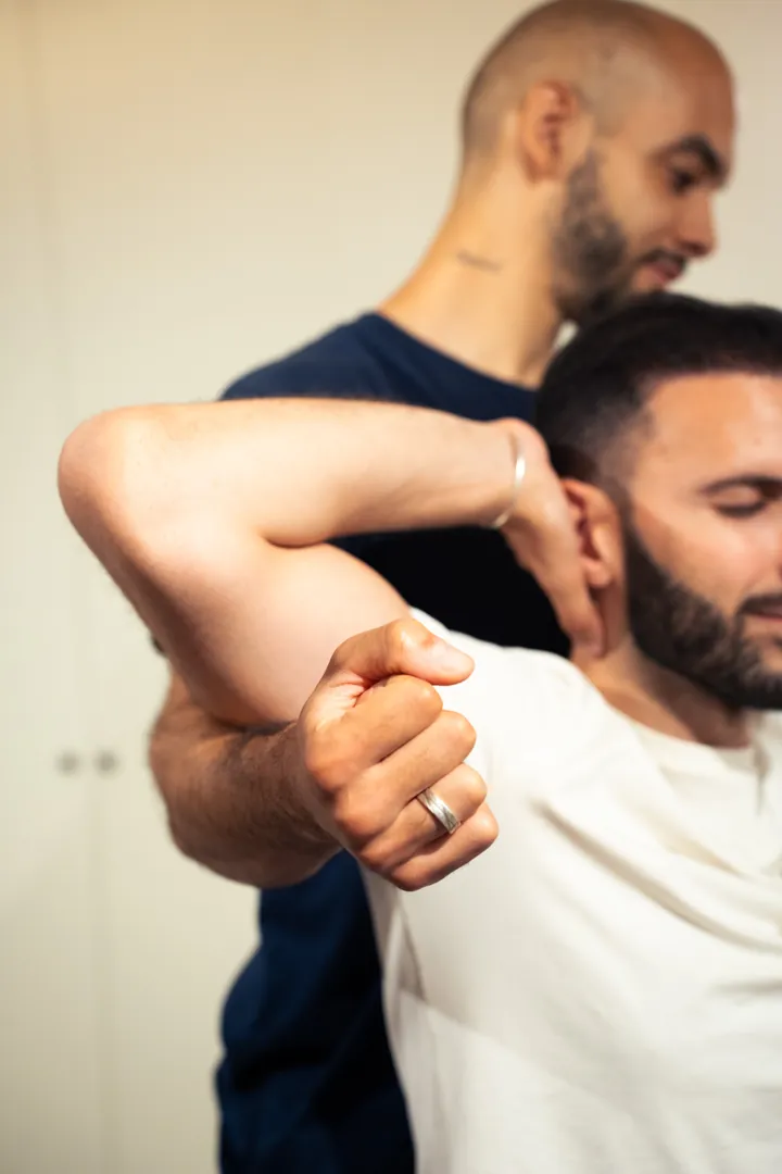 Un flexologue tient le bras d'un client pendant un étirement de l'épaule